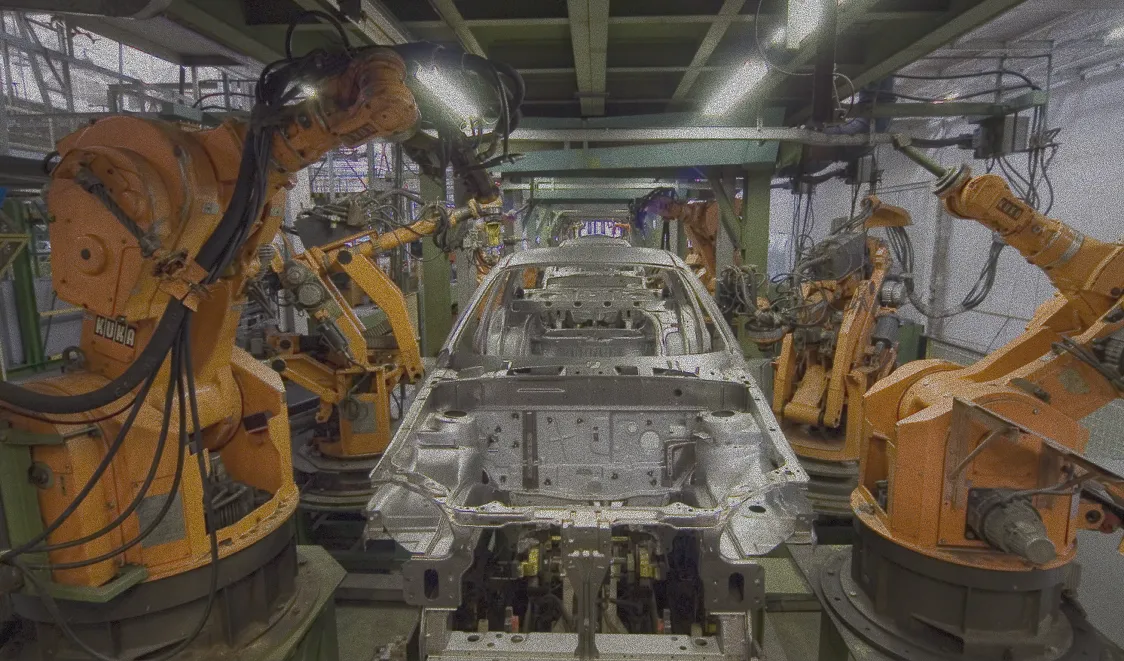 Orange industrial robots assemble a car body